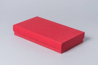 Gri arkaplanlı kırmızı karton hediye kutusu.