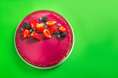 Yeşil arka planda çilek desenli kırmızı kremalı pasta.