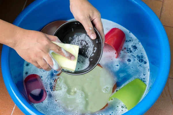 Women hand wash dishes in basin