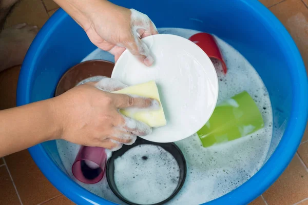 Women hand wash dishes in basin