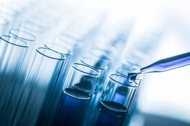 Laboratuvardaki deney tüpünün üzerinde borular, laboratuvar deneyleri için kimyasal örnekler bırakıyor.