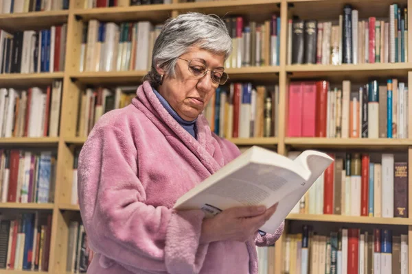 Ανώτερος γυναίκα διαβάζοντας ένα βιβλίο στο σπίτι. συμπυκνωμένη έκφραση. Α — Φωτογραφία Αρχείου