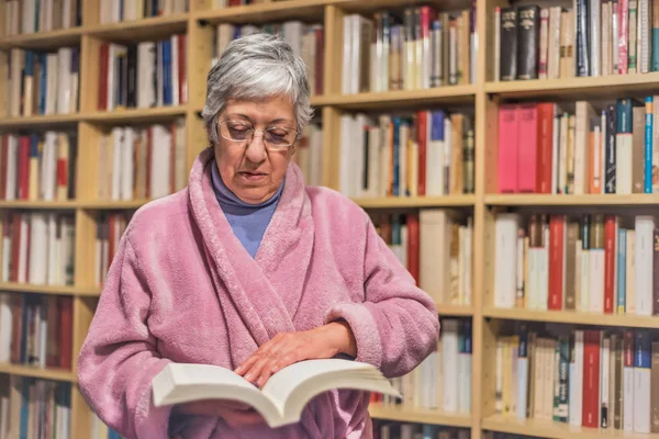Starší žena čte knihu doma. koncentrovaný výraz. A — Stock fotografie
