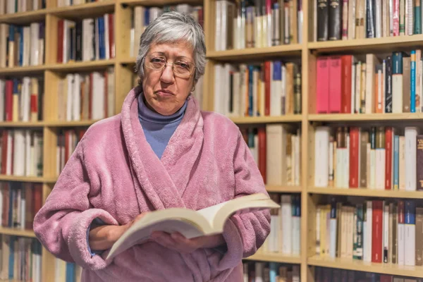 Старша жінка читає книжку вдома. Серйозний вираз. Прокляття — стокове фото