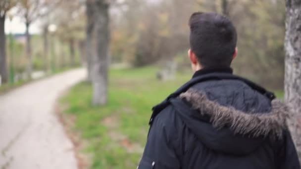 Молодой человек ходит по осеннему парку . — стоковое видео
