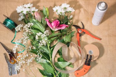 Bir çiçekçinin iş yerinde. Bir buket çiçek ve bahçe aletleriyle dolu bir masa..