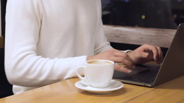 Hombre joven con ordenador portátil y taza de café en la cafetería . — Vídeos de Stock