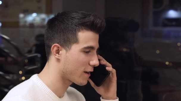 Portret van een jongeman aan de telefoon in de coffeeshop. — Stockvideo