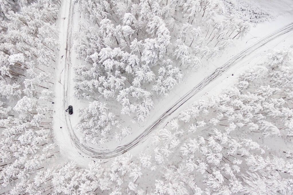 Car on road in winter trough a forest covered with snow. Aerial photography of a road in wintertime trough a forest covered in snow. High mountain pass. 
