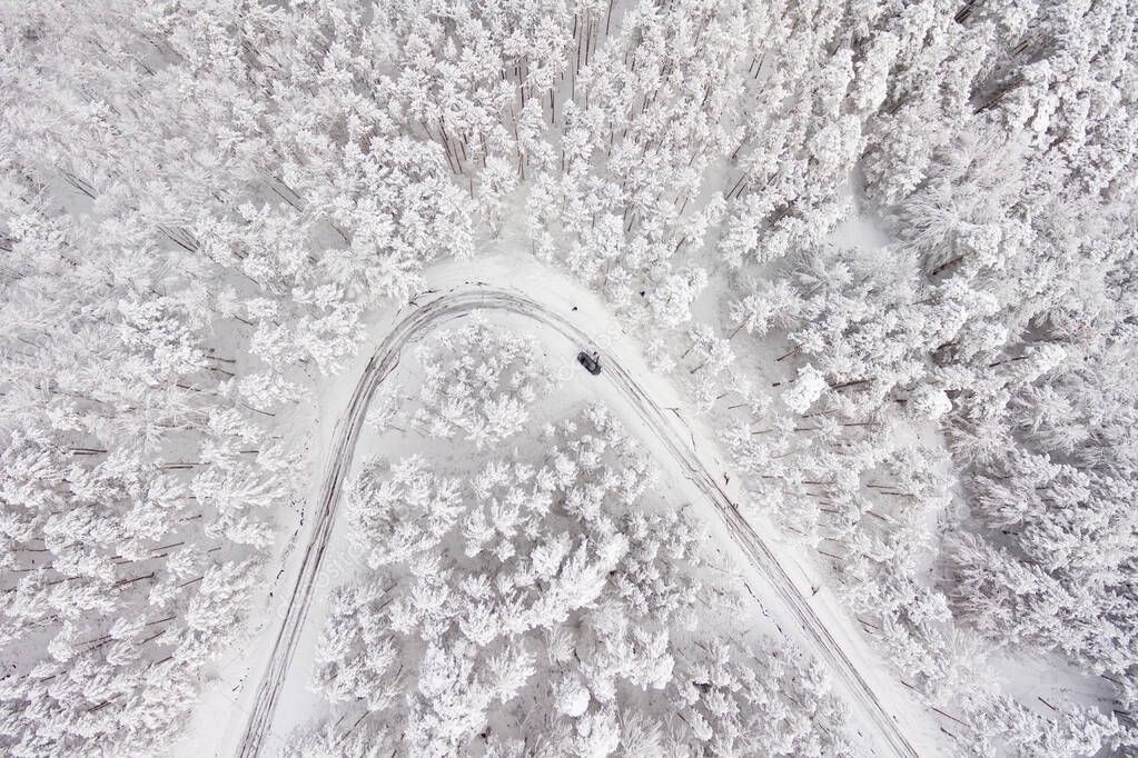 Car on road in winter trough a forest covered with snow. Aerial photography of a road in wintertime trough a forest covered in snow. High mountain pass. 