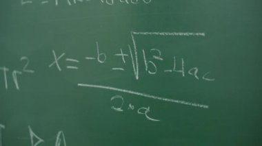 Öğretmen matematik denklemleriyle tahtayı temizliyor. 