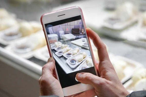 Mujer está tomando móvil foto de la preparación de comida asiática en un restaurante escaparate . — Foto de Stock