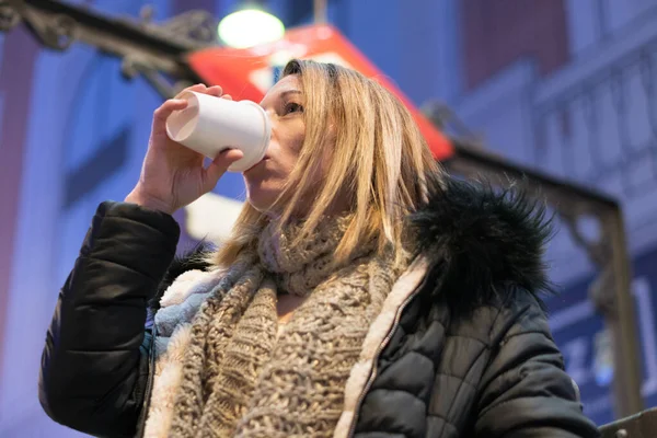 Mooie vrouw in de nachtstad die koffie drinkt. Stadsverlichting achtergrond. — Stockfoto