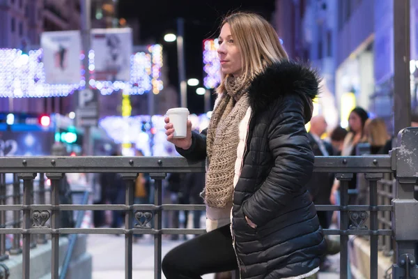 Een vrouw met koffie op straat. Mooie modieuze jonge vrouw met koffie in de nacht stad. — Stockfoto