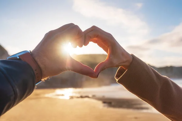 Szoros kép a pár kéz, hogy szív alakú a strandon, őszi szezonban. Boldog szerelmespár.. — Stock Fotó