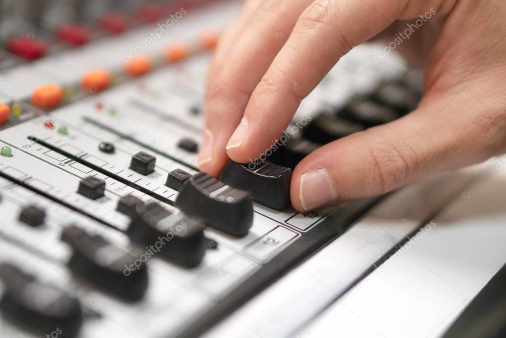 Male hand on control Fader on console. Sound recording studio mixing desk with engineer or music producer.