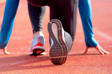 Koşu pistinde yarışa hazırlanan bir sporcunun arka görüntüsü. Stadyumda yarış başlatmak üzere olan bir sporcunun ayakkabısına odaklan..