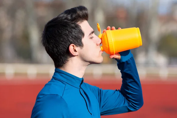 Atleta beber agua en una pista de atletismo . — Foto de Stock