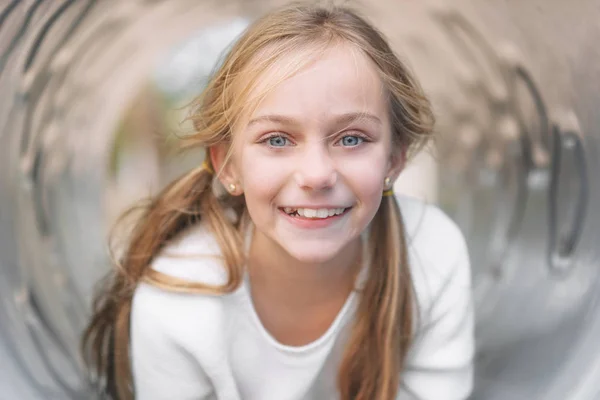 Mooi, klein meisje, hebben plezier, liggend op pijp op kinderen speelplaats. — Stockfoto