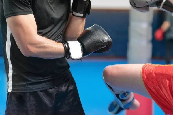 Ung man fighter, träning kick boxning med sin tränare, slåss i ringen. — Stockfoto