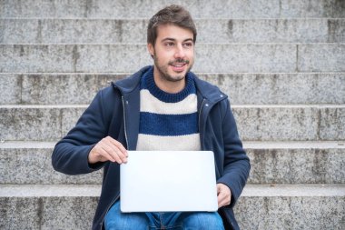 Yakışıklı hippi modern iş adamı, şehirde dizüstü bilgisayar kullanıyor, pozitif ifadeli..