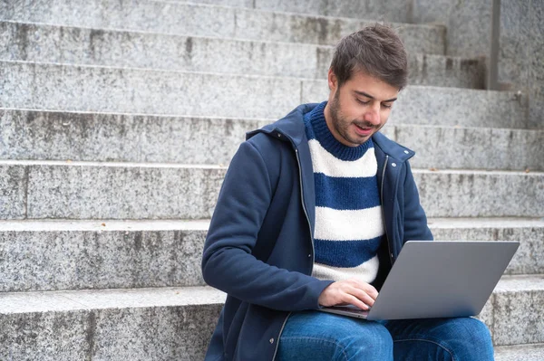 Handsome hipster modern businessman, using laptop in the city, with positive expression. — Stock Photo, Image