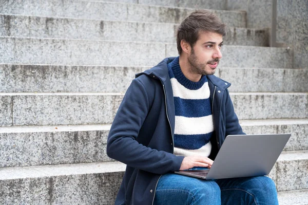 Handsome hipster modern businessman, using laptop in the city, with positive expression. — Stock Photo, Image