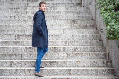 Genç çekici bir adamın yatay portresi geriye doğru bakıyor. Modern ve şık adam dizüstü bilgisayarın ellerini tutuyor.. 