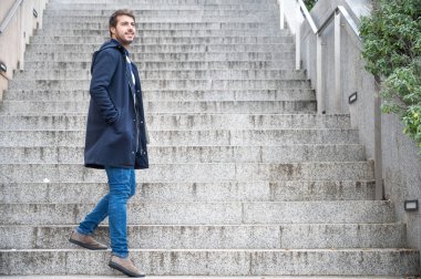 Genç çekici bir adamın yatay portresi geriye doğru bakıyor. Modern ve şık adam dizüstü bilgisayarın ellerini tutuyor.. 