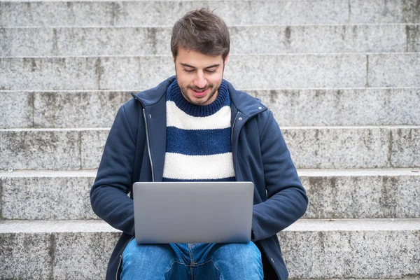 Handsome hipster modern businessman, using laptop in the city, with positive expression. — Stock Photo, Image