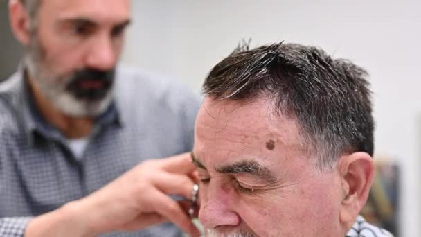 Peluquero recortar el pelo del anciano en la peluquería . — Vídeos de Stock