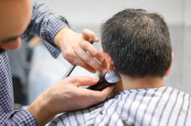 Berber berber dükkanında yaşlı bir adamın saçını buduyor..