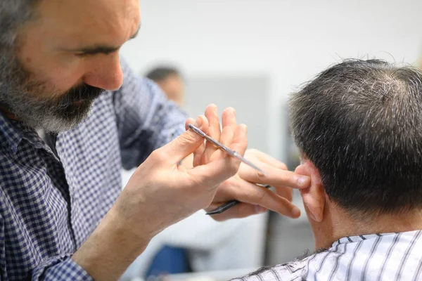 Kapper trimmen haar van oude man bij kapperszaak. — Stockfoto