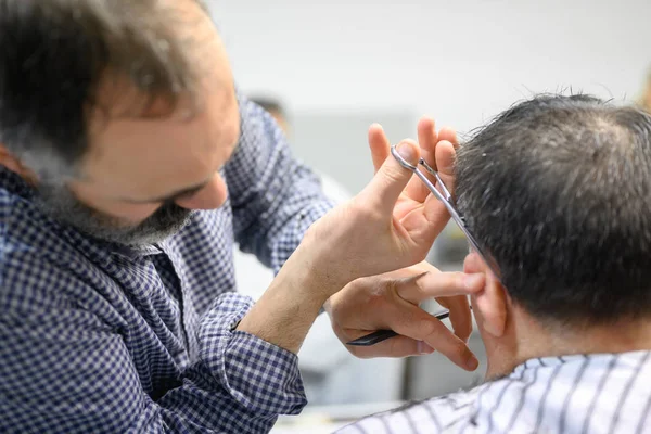 Kapper trimmen haar van oude man bij kapperszaak. — Stockfoto