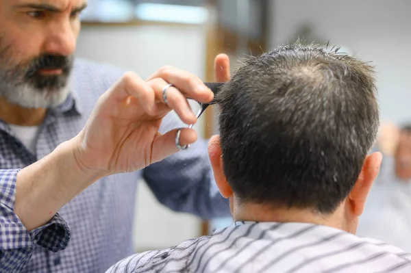 Kapper trimmen haar van oude man bij kapperszaak. — Stockfoto