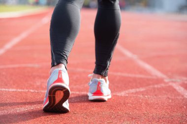 Koşu parkurunda koşmaya hazırlanan atletik kişi, arka plan görünümü.
