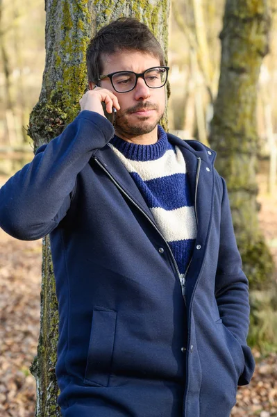 Серьезный человек, разговаривающий по мобильному телефону в осеннем парке . — стоковое фото