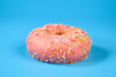 Mavi arka planda pembe buzlu çörek. Tatlı tatlı üst görünümü.