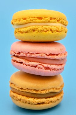 Mavi arka planda pastel renkli tonda tatlı Fransız badem kurabiyeleri..