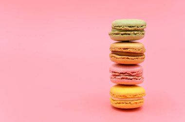 Pembe arka planda pastel renkli tonda tatlı Fransız badem kurabiyesi yığını..