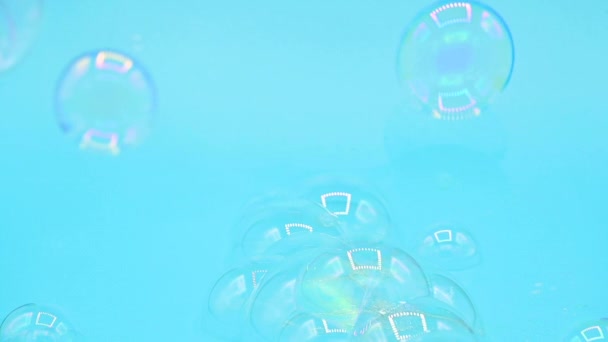 Burbujas de jabón reales volando sobre fondo pastel azul. — Vídeo de stock