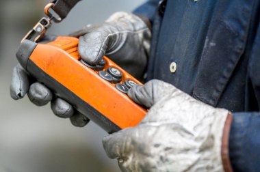 Fabrikadaki vinç için uzaktan kumanda düğmesine erkek el basar, yakın plan. İşçi eliyle vinç ve diğer kaldırma ekipmanlarının elektrik kontrol paneli.