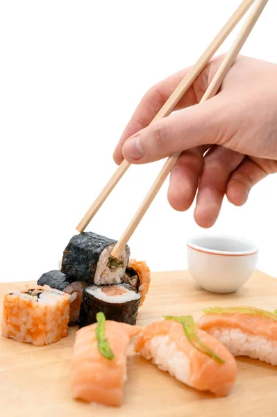 Japanese restaurant food. hand pick sushi roll with chopsticks on white isolated background.
