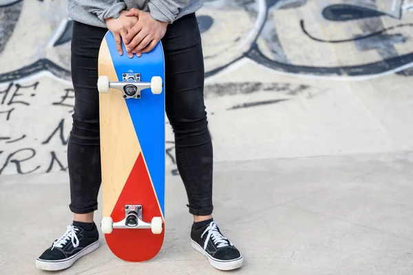 Close up de jovem irreconhecível segurando longboard ou skate no parque . — Fotografia de Stock