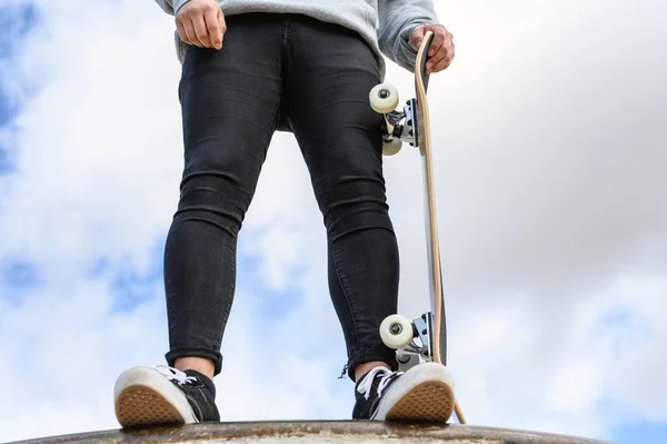 Detailní záběr nerozpoznatelného mladého muže držícího longboard nebo skateboard v parku. — Stock fotografie