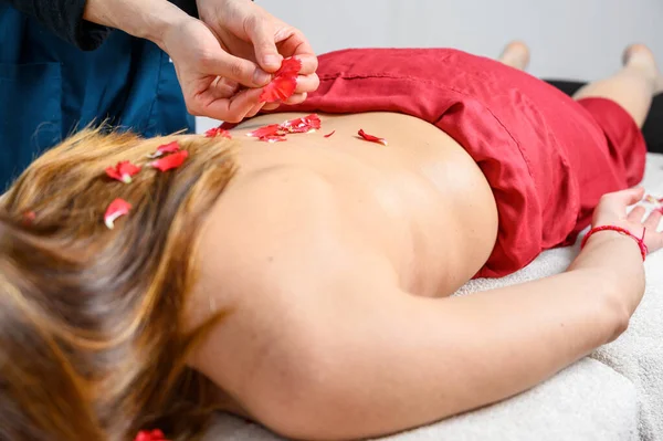 Hermosa mujer recibiendo masaje y tratamiento de spa con pétalos de flores en el salón de spa . —  Fotos de Stock