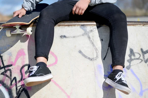 공원에서 스케이트보드를 들고 앉아 있는 알아볼 수없는 젊은이를 가까이 서 본 것이다. — 스톡 사진