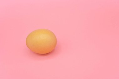 Pembe arka planda çiğ kahverengi tavuk yumurtası..