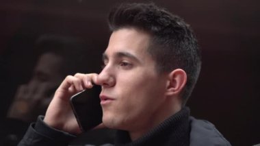 Modern şehir merkezinde, sokakta cep telefonuyla konuşan yakışıklı bir gencin portresi. İnsanlar ve teknoloji.