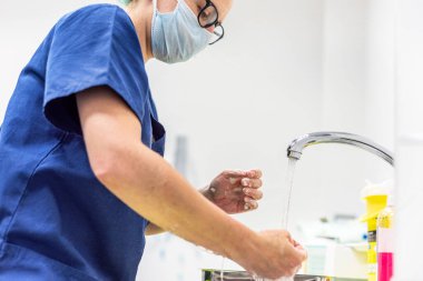 Coronavirus önleme. Covid-19 enfeksiyonu olan bir hastayı tedavi ettikten sonra ellerini yıkayan hemşire. Tıbbi dezenfekte işlemi.